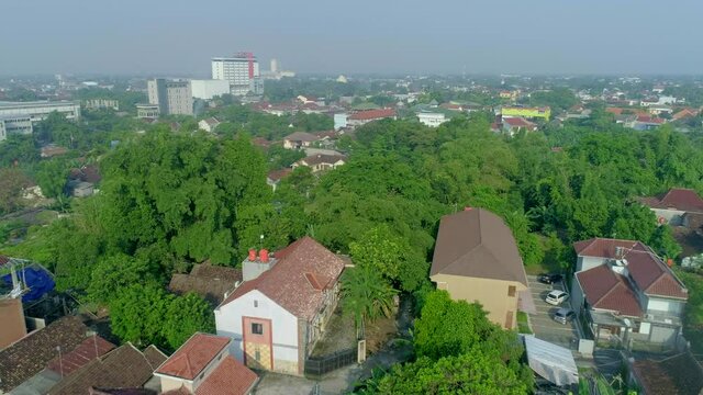 Aerial footage cityscape view Yogyakarta city from drone flying backward dolly movement with buildings, green trees and neighbourhood