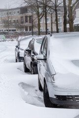 Fototapeta premium Cars parked in a street in a modern suburb covered with snow after a snow storm