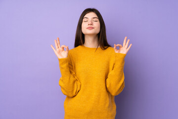 Young Ukrainian teenager girl over isolated purple background in zen pose