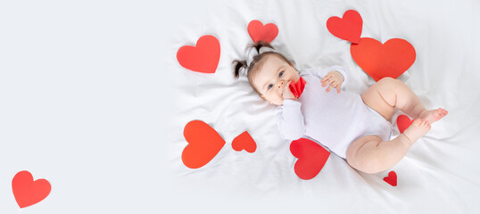 baby among hearts on the bed, banner, place for text, valentine's day concept