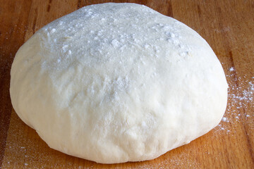 Raw dough for pizza on wooden board