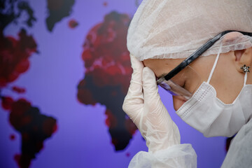 Uma mulher com a m&atilde;o na cabe&ccedil;a com luva cirurgica pensando e fundo desfocado.