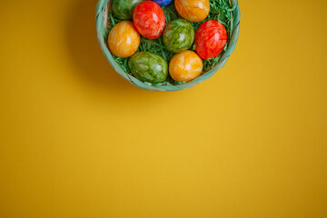 Easter card. Flat lay composition with easter eggs in a basket on yellow background.