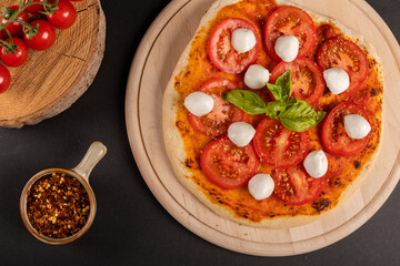 Tasty pizza with cooking ingredients on background.