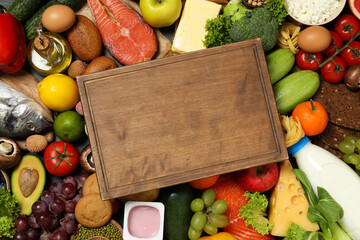 Wooden board among different products, top view with space for text. Healthy food and balanced diet