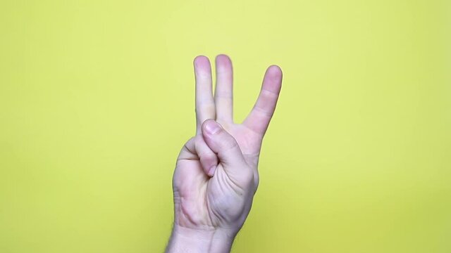 Closeup of isolated on yellow adult male hand counting from 0 to 5. man shows fist fist, then one, two, three, four, five fingers. Manicured nails painted with beautiful pink polish. Math concept.