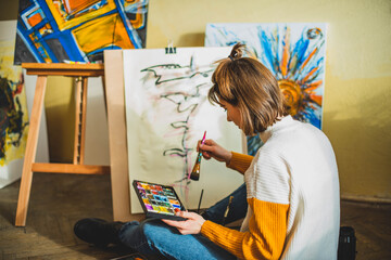 Beautiful woman painting. Girl in Painting Studio. Talented Female Artist Working on a Modern Abstract Oil Painting, Gesturing with Broad Strokes Using Paint Brush. Dark Creative Studio