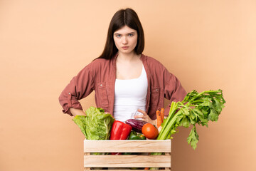 Young farmer girl with freshly picked vegetables in a box angry