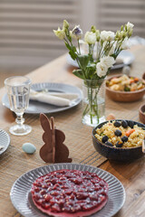Close up background of elegant Easter dinner table set with Spring flowers and delicious homemade food, copy space
