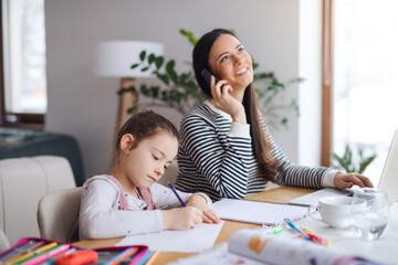 Mother with school girl indoors at home, distance learning and home office.