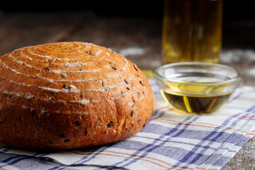 Closeup on loaf of rustic bread with olive oil on the wooden table