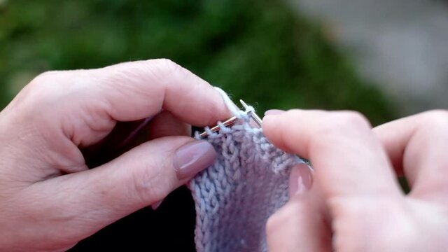 Mature caucasian female hands knitting a scarf.