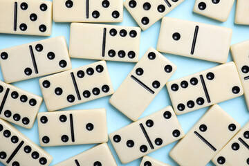 Classic domino tiles on light blue background, flat lay