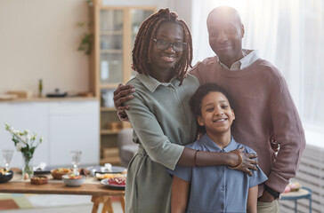 Portrait of happy African-American family looking at camera while posing indoors in cozy home...