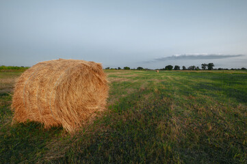 haystack on green field under the beautiful blue cloudy sky at  sunrise. foggy morning. summer (autumn) landscape