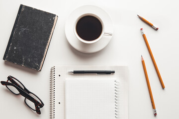 Office desk table with supplies, coffee cup and flower. Top view
