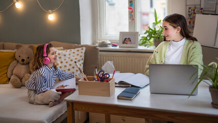 Sisters schoolgirls learning online indoors at home, coronavirus concept.
