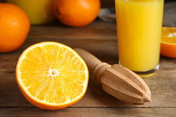 Cut fresh ripe orange, reamer and juice on wooden table, closeup