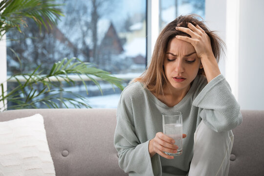 Woman holding glass of medicine for hangover at home