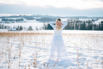 Fototapeta na wymiar Frau in weißem Schneekleid Haute Couture Hochzeitskleid Designerkleid weiß Winterlandschaft Schnee kalt Freude lacht