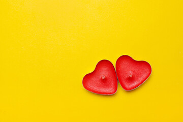 Candles in the form of hearts on a yellow background . Red candles. Red hearts. Yellow background. Copy space. Valentine's Day. Holiday. An article about celebrating Valentine's Day..