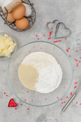 Preparing of heart-shaped cookies with pink chocolate glaze for Valentine's Day. Flour, powdered sugar and almond flour in a bowl. Recipe step by step. Top view.