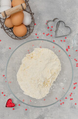 Preparing of heart-shaped cookies with pink chocolate glaze for Valentine's Day. Flour, powdered sugar, almond flour and butter in a bowl. Recipe step by step. Top view.