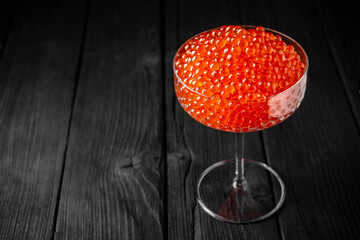 Red caviar in a crystal bowl on a black background. Delicacy product of the highest quality.
