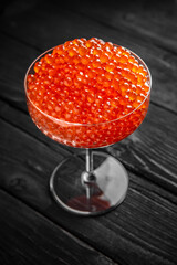 Red caviar in a crystal bowl on a black background. Delicacy product of the highest quality.