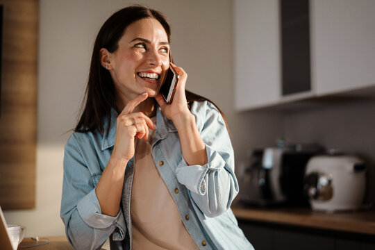 Happy charming woman smiling while talking on smartphone