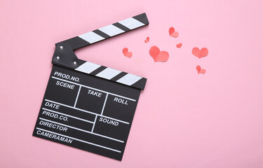 Movie clapperboard and hearts on a pink background. Filmmaking concept. Top view