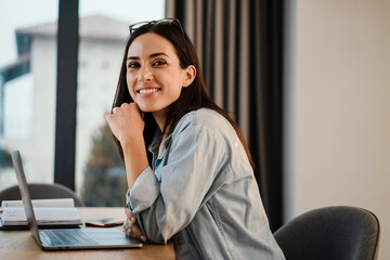 Happy charming woman smiling while working with laptop at home