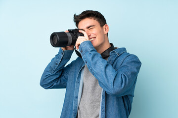 Teenager photographer man isolated on blue background