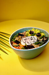 Top view of Bibimbap, a classic Korean meal. Rice is topped with seasoned vegetables, meat and a sunny side up fried egg on top. Spicy chili sauce can be added to finish off this savoury Asian dish.
