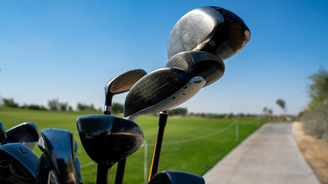 Background image of multiple golf sticks on the behind of a golf cart.
