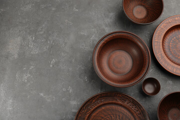 Set of clay dishes on grey table, flat lay. Space for text
