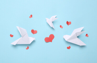 Origami doves with hearts on a blue pastel background. Top view
