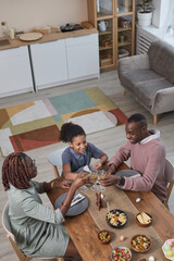 Vertical high angle portrait of modern African -American family enjoying dinner together while celebrating Easter at home, copy space