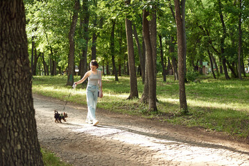 Fototapeta premium Active young woman with a dog for a walk in a beautiful summer nature. Outdoor