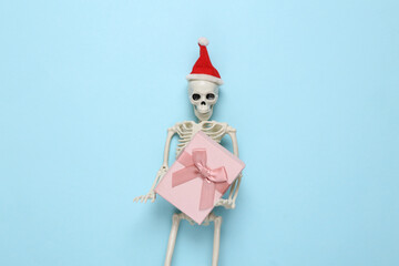 Skeleton with santa hat holding a gift box on a blue background