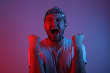 Emotional Bearded Man in foil hat in blue red neon light.