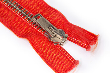 Slider of red metal zipper close-up in selective focus