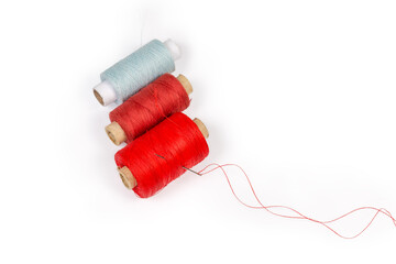 Different threads spools and hand sewing needle with red thread