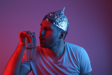 Emotional Bearded Man in foil hat is caught finger in mousetrap in red-blue neon light