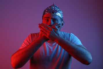 Crazy Bearded Man in aluminum foil cap in red blue neon light. Conspiracy
