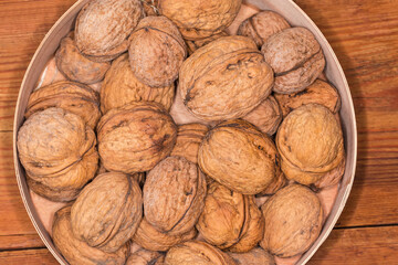 Top view of walnuts in shells in wooden round box