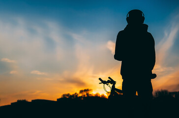 Silhouette of a cyclist and a bicycle in the spring against the background of the sunset, spring lifestyle copy space
