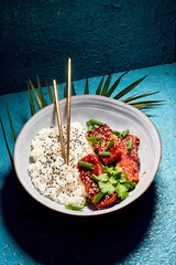 Delicious Korean tofu. Fried tofu in a spicy glaze, sprinkled with green onions and coriander. Served on a beautiful white plate with borders and chopsticks. And it all fits nicely with the blue backg