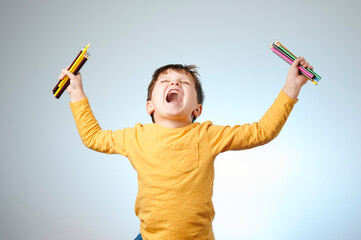 Fototapeta na wymiar Happy boy with color pencils on light background.