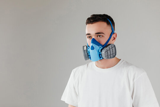 A man in a respirator mask with an increased degree of protection against harmful environmental factor, chemicals or covid19. Full face mask. Isolated on a grey background.